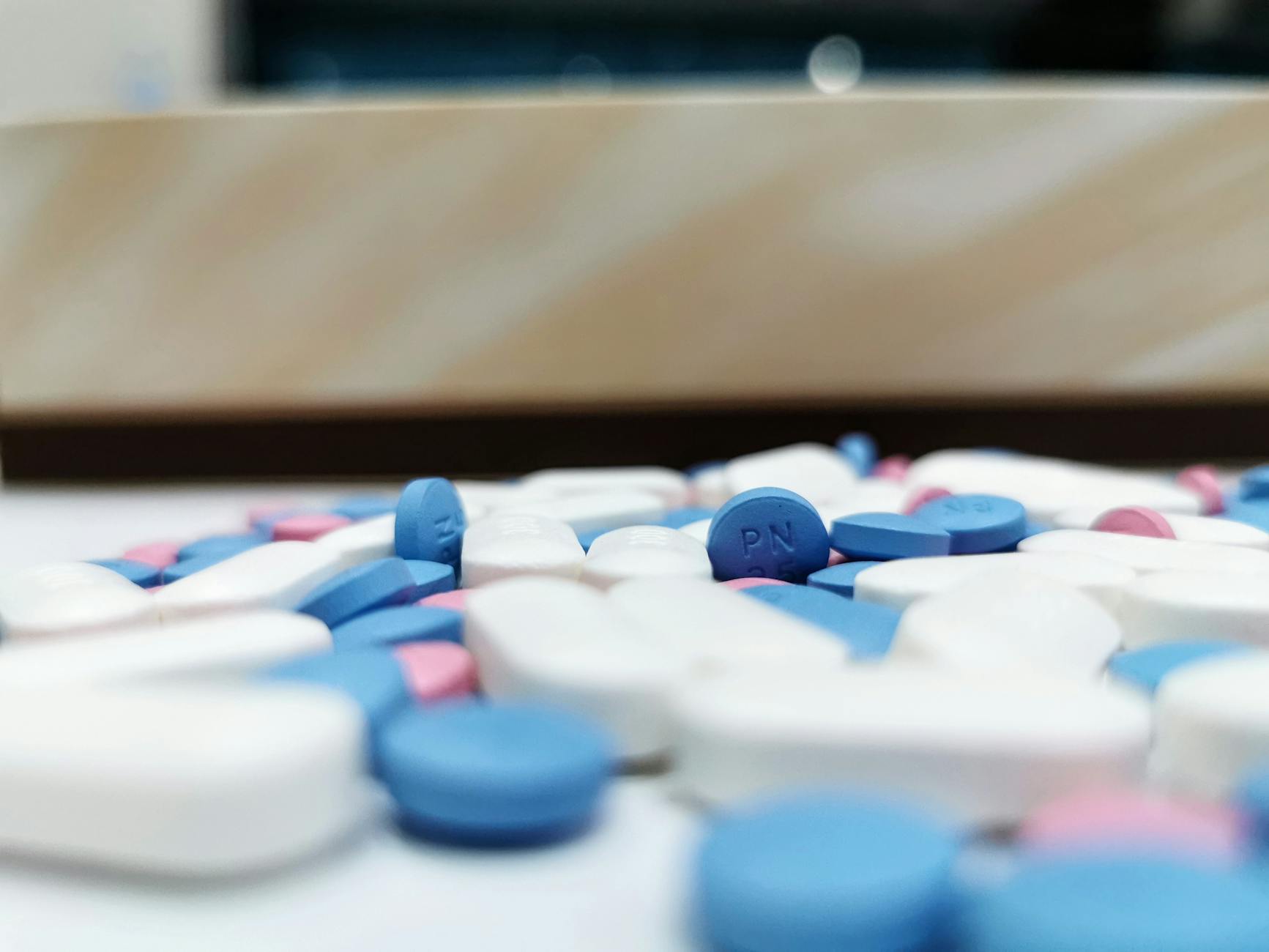 Pharmaceutical pills and tablets scattered on white surface representing generic drug market