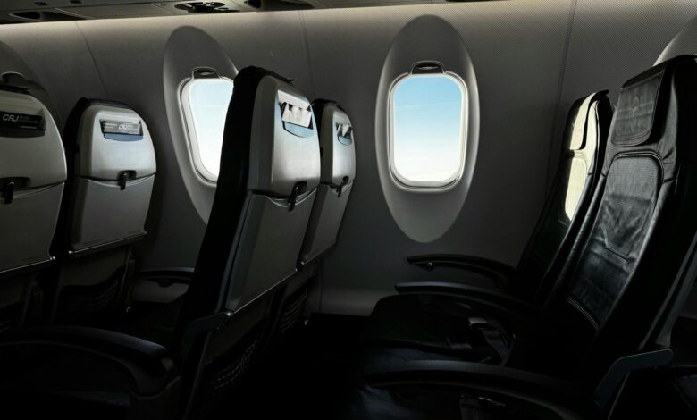 Modern airline cabin interior showing rows of passenger seats with overhead compartments