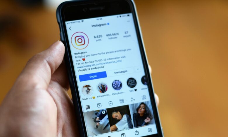 Person holding smartphone displaying social media feed with sponsored content posts