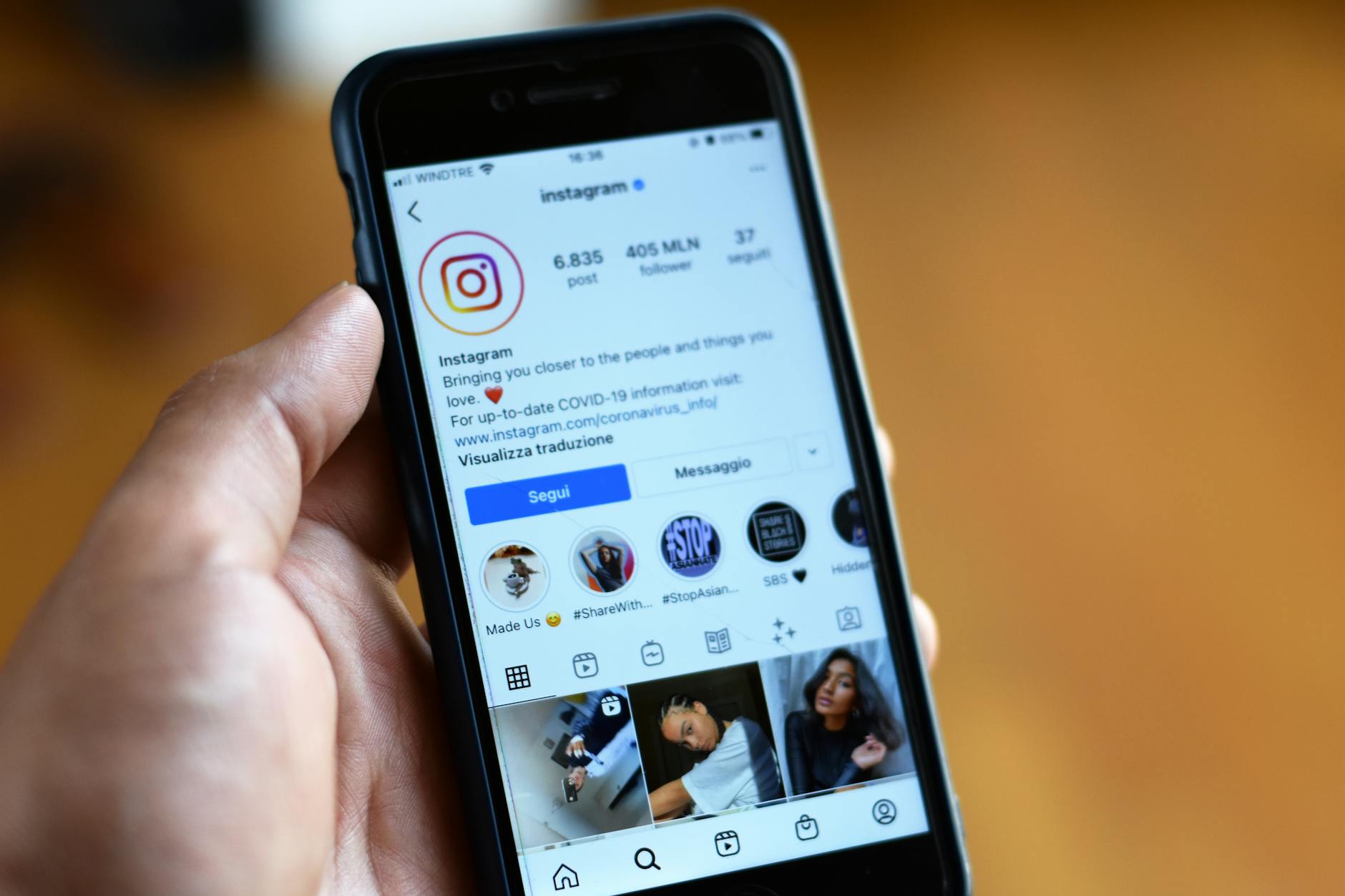 Person holding smartphone displaying social media feed with sponsored content posts