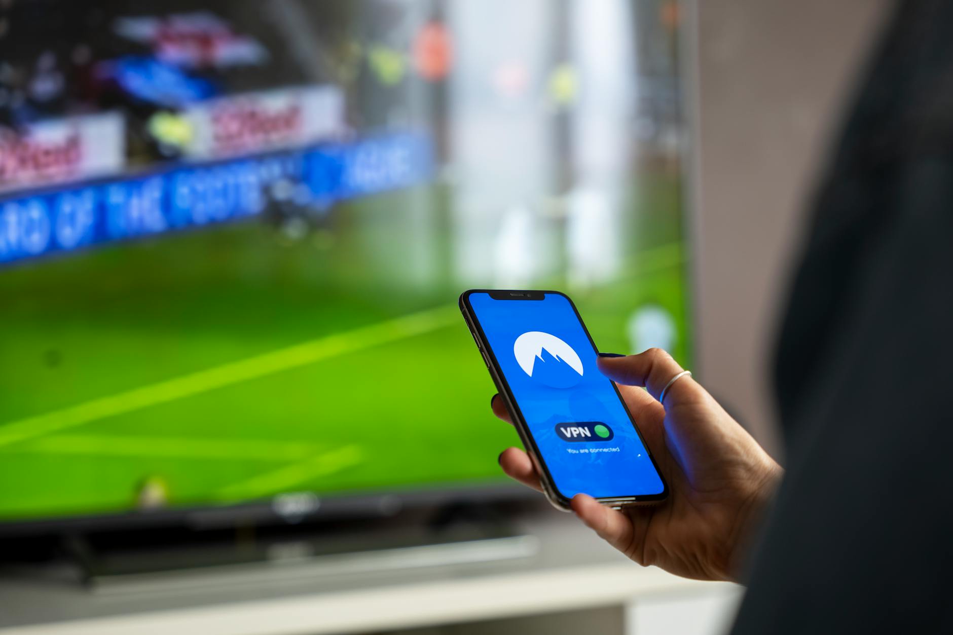 Person holding remote control watching streaming content on television screen