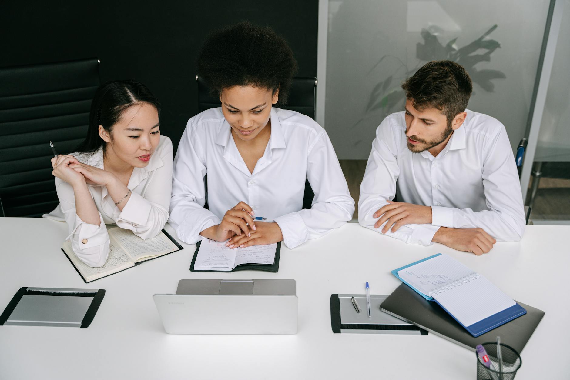 Modern office workspace showing employees collaborating on project with laptops and documents