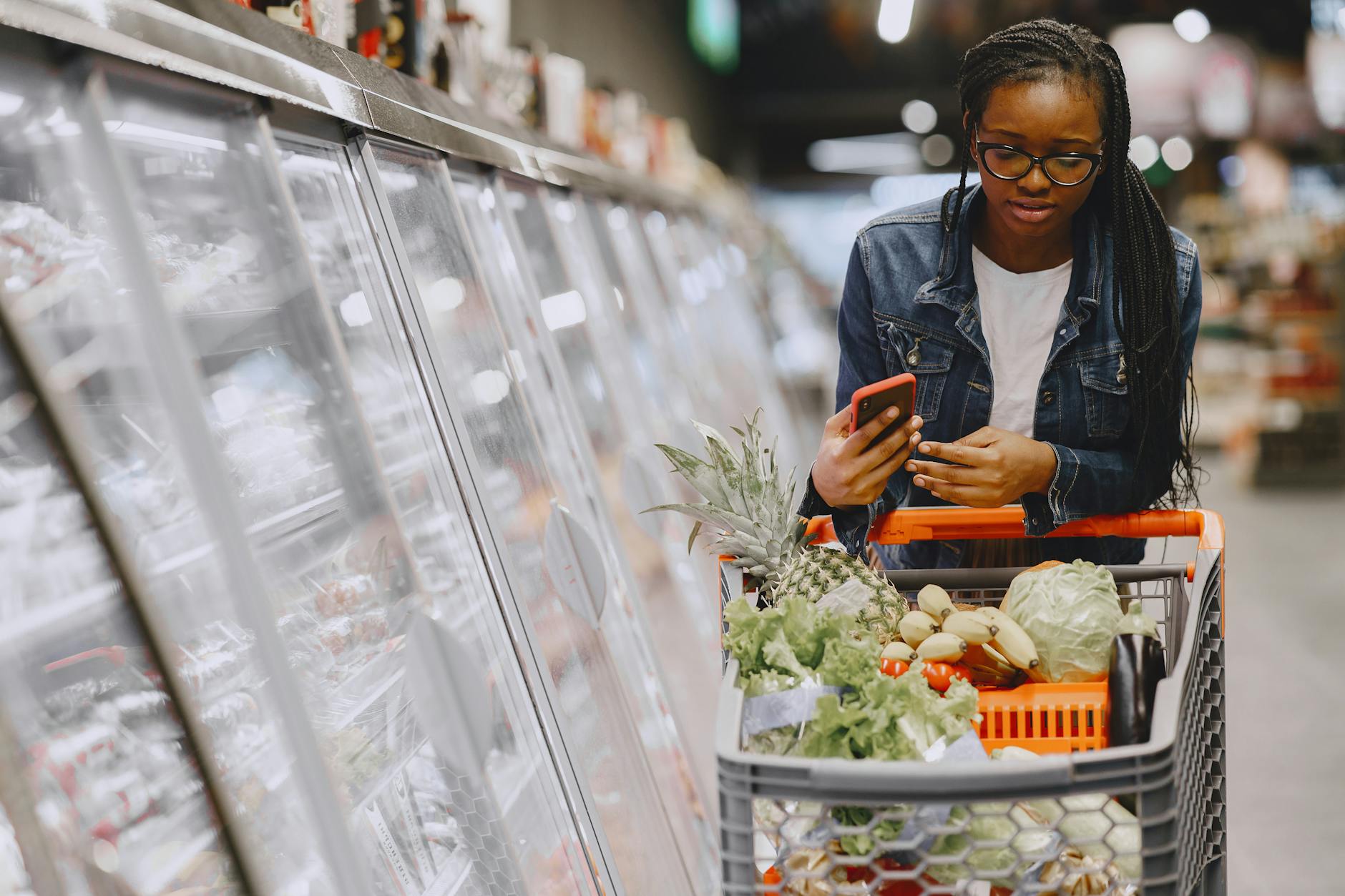 Young woman using smartphone while shopping for clothes in modern retail store