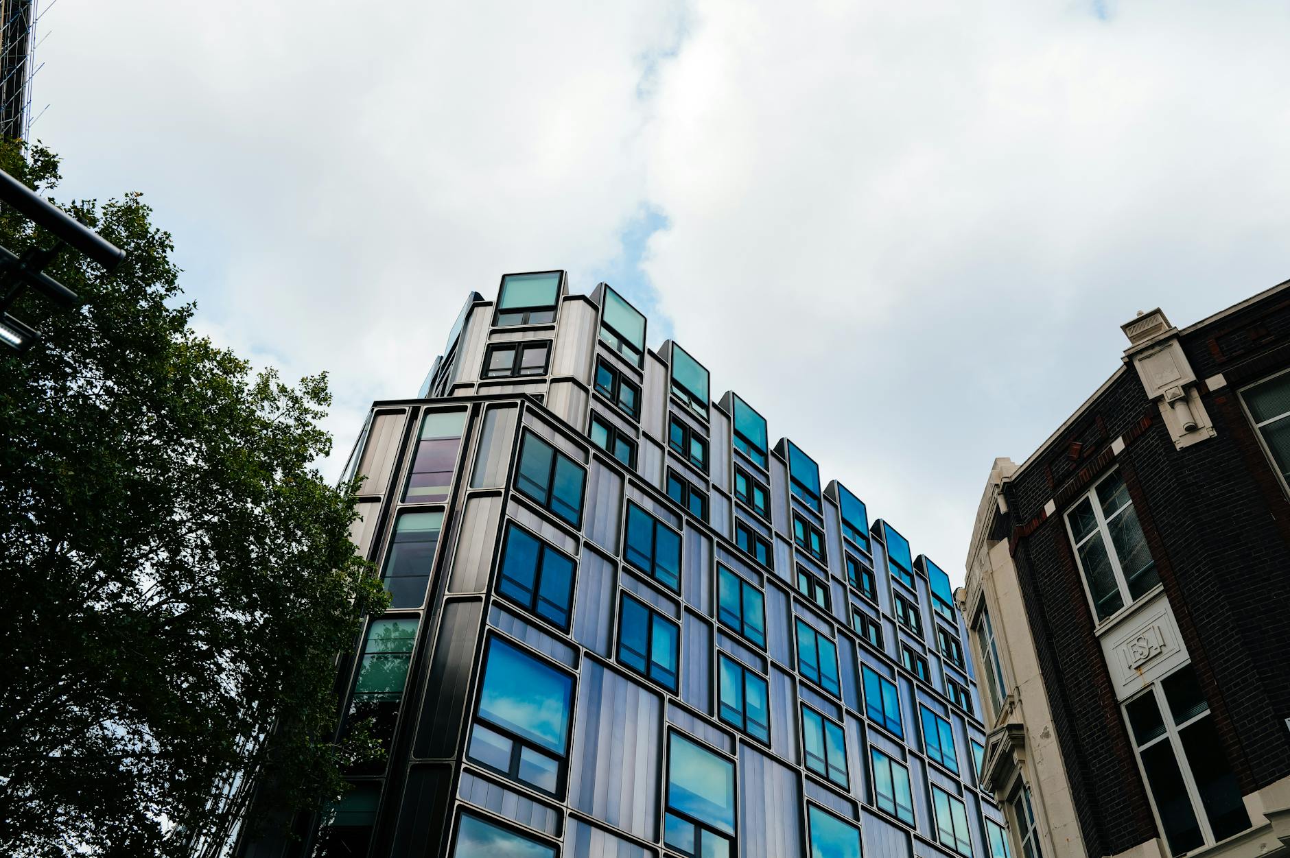 Glass office tower exterior reflecting sky, representing commercial real estate holdings