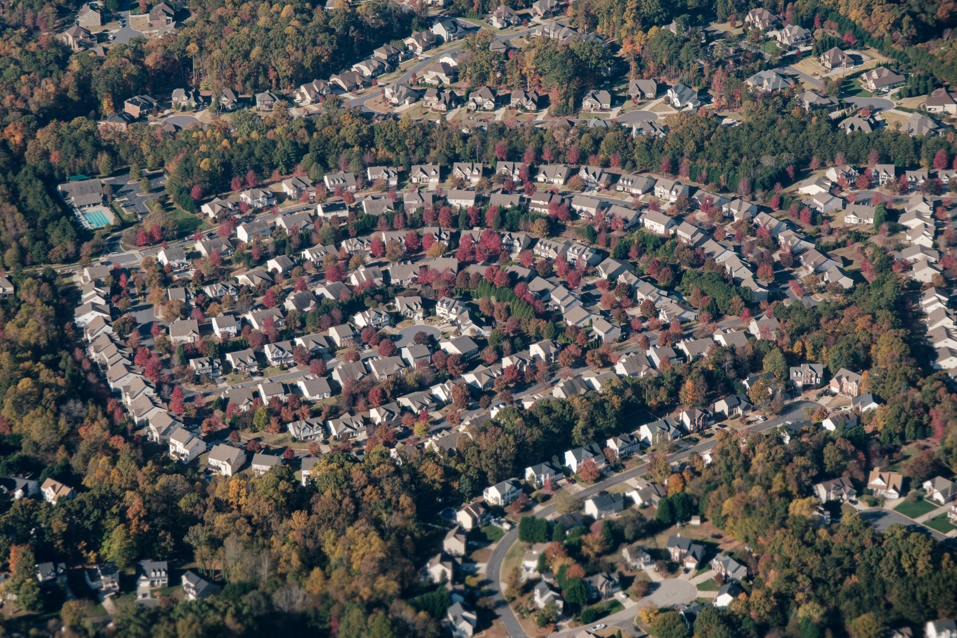 Aerial photograph of a suburban housing development with rows of new homes and undeveloped land