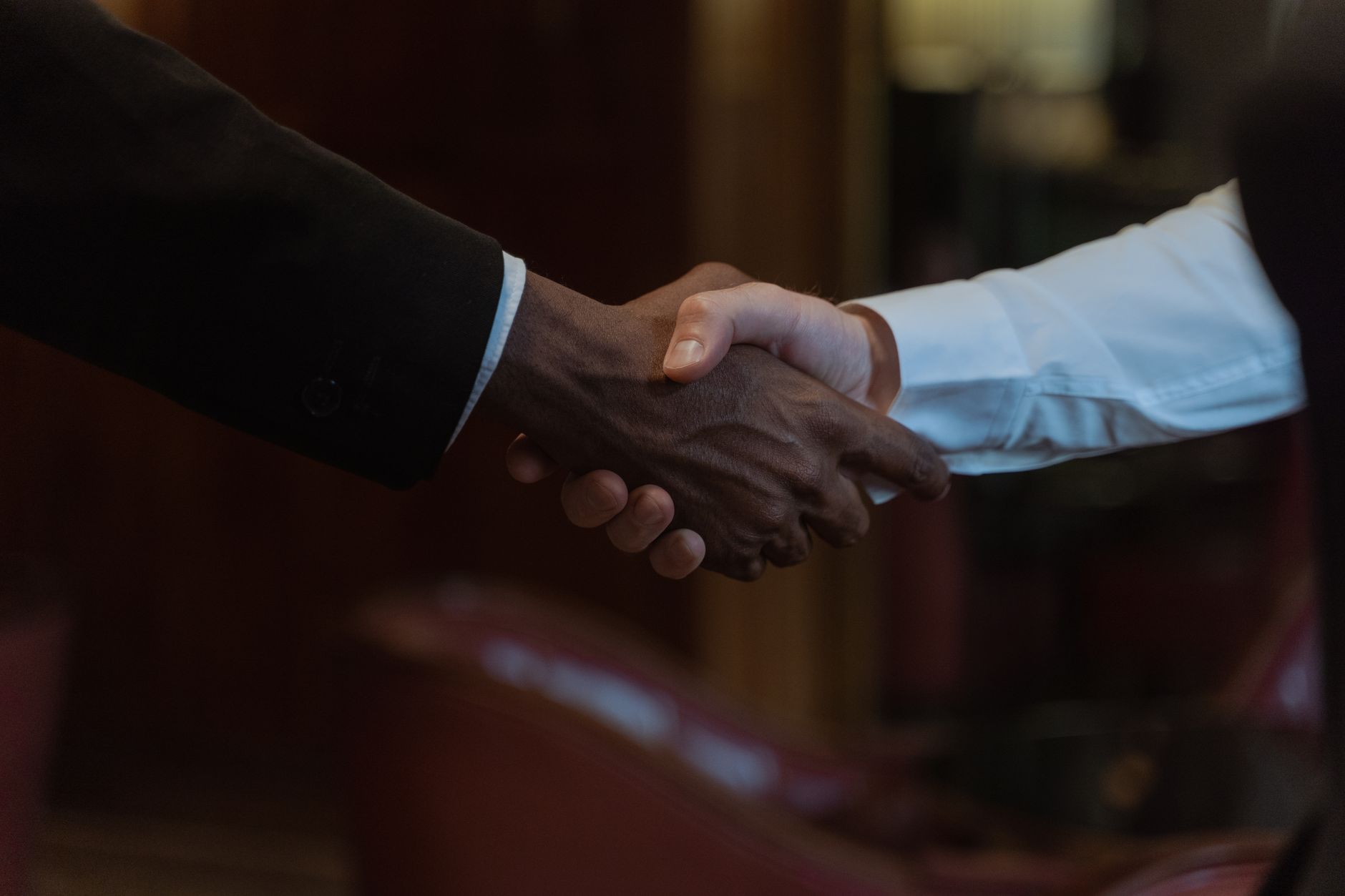 Two business professionals shaking hands over a signed agreement