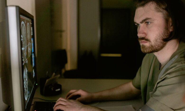 Radiologist reviewing medical imaging scans in a darkened reading room