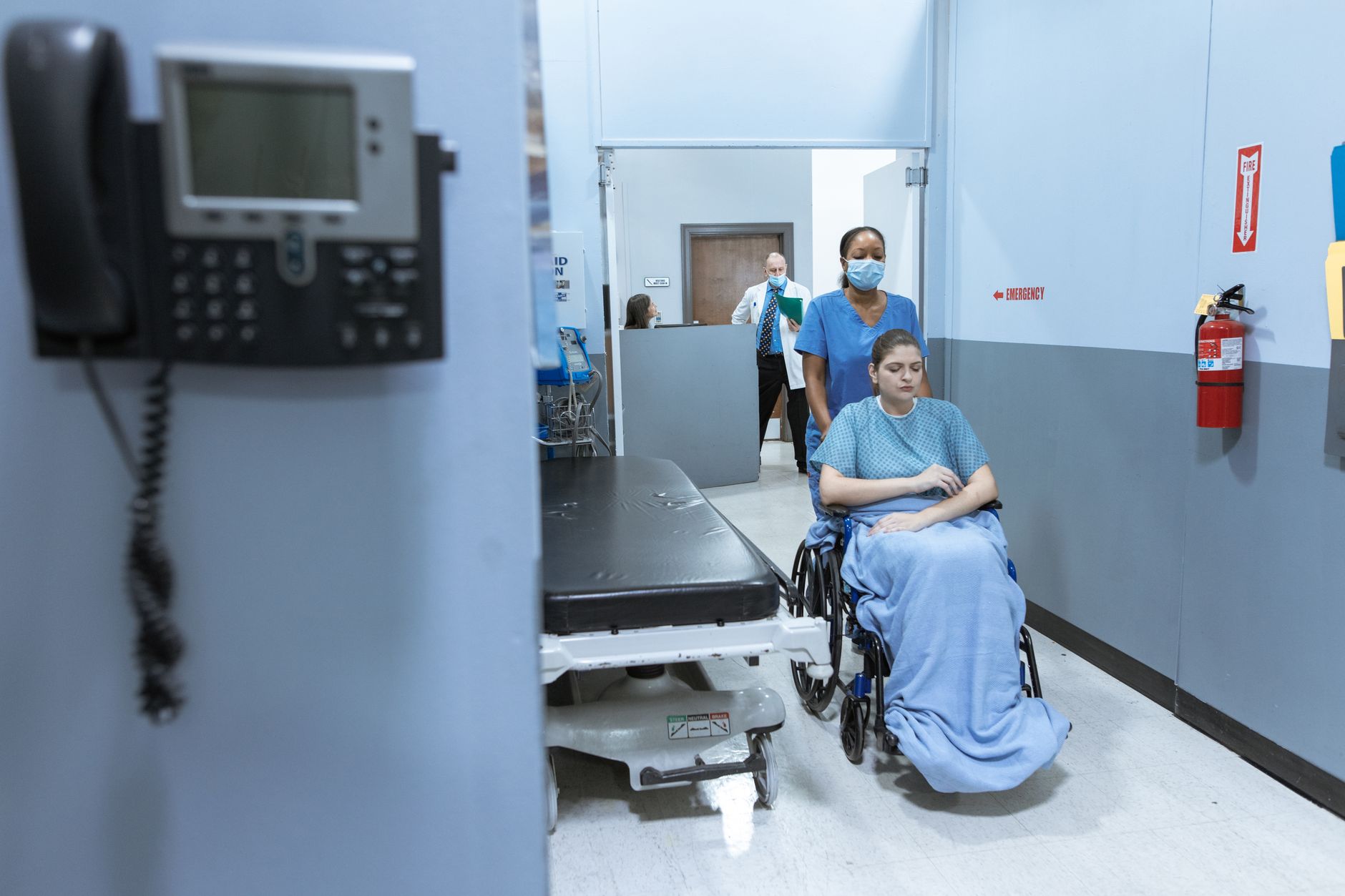 Medical technicians walking through a hospital corridor near diagnostic equipment