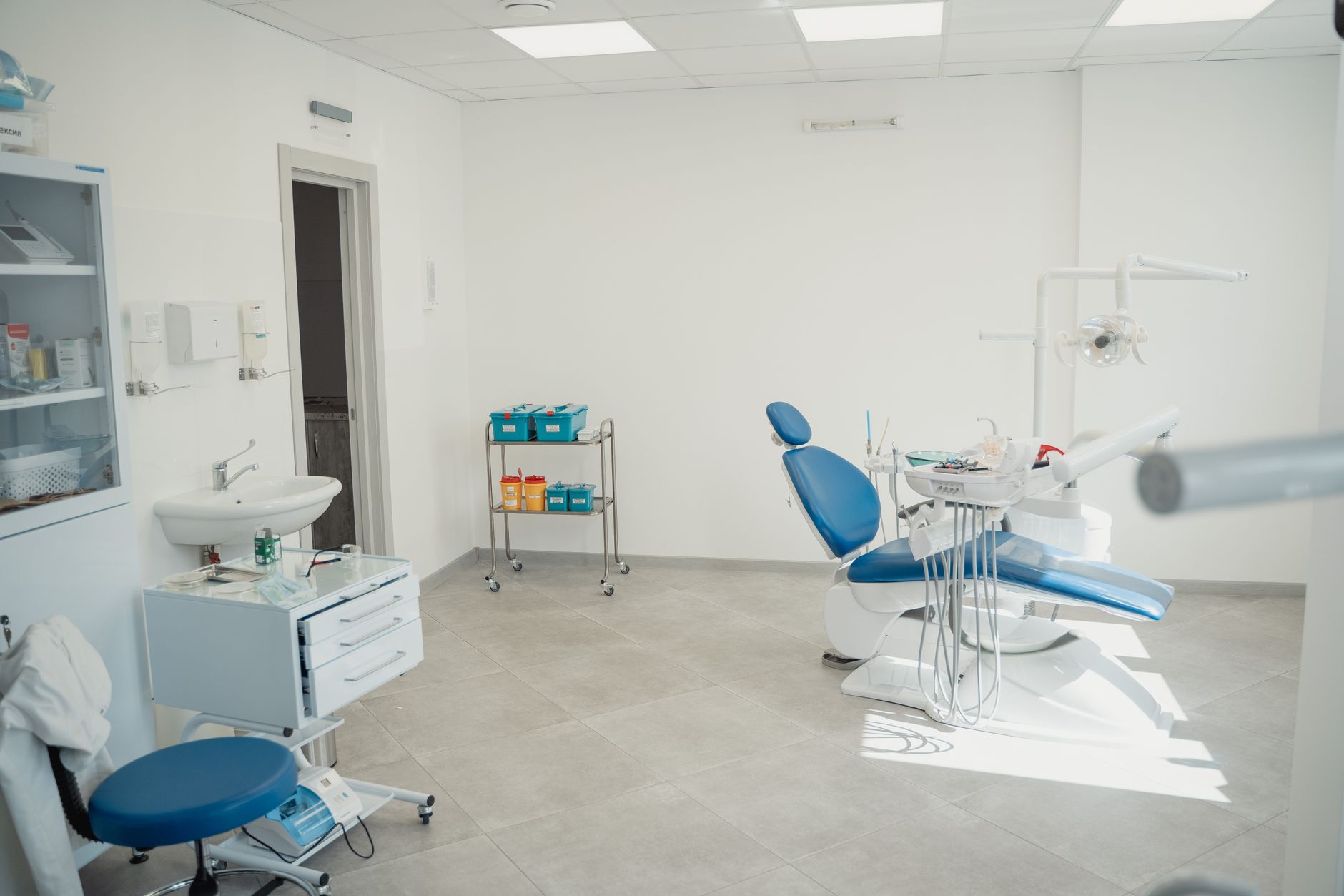 Interior of a small medical practice office with exam room visible in background